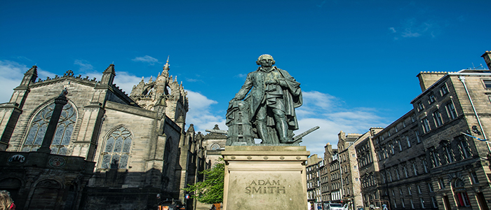 Adam Smith statue in Kirkcaldy from the front, with buildings in the background and blue sky