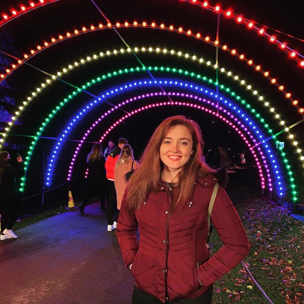 Lucy standing under a rainbow light tunnel
