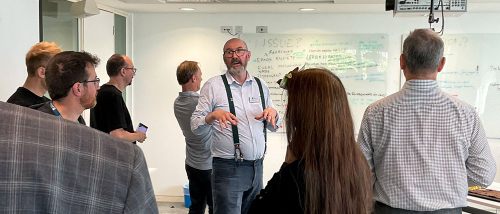 David Hughes speaking among a group of listening people