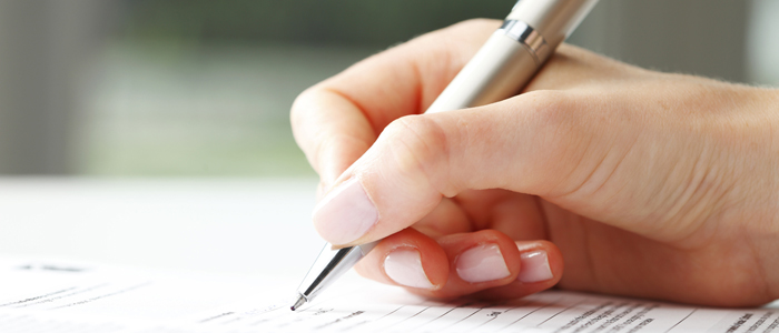 Photo of a hand holding a pen and completing an application form