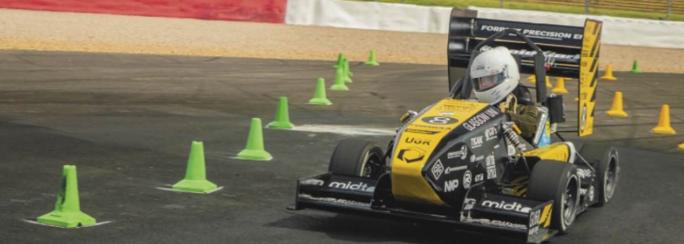 student racing car driving beside green cones